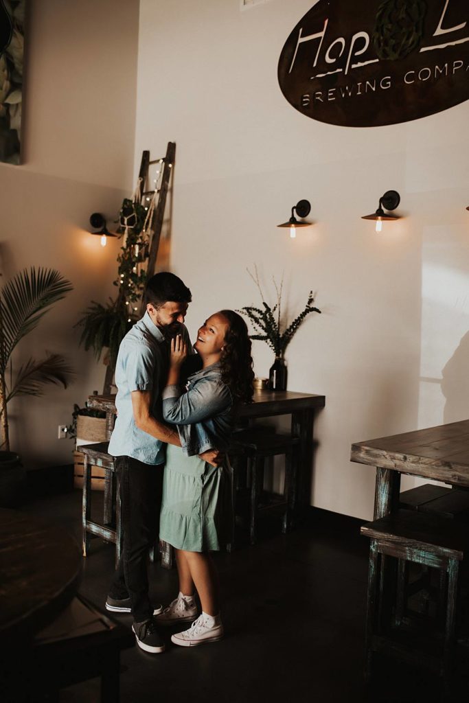 Couple hugging during engagement session inside brewery