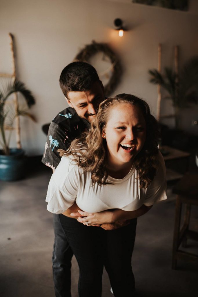 Boy grabbing girl from behind during engagement session at brewery