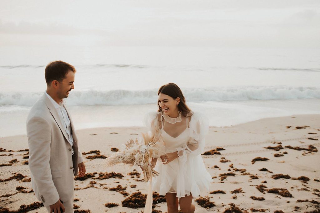Bride and groom laughing on beach