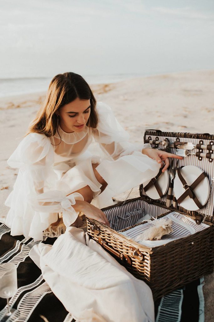 Bride setting up an elopement picnic on beach