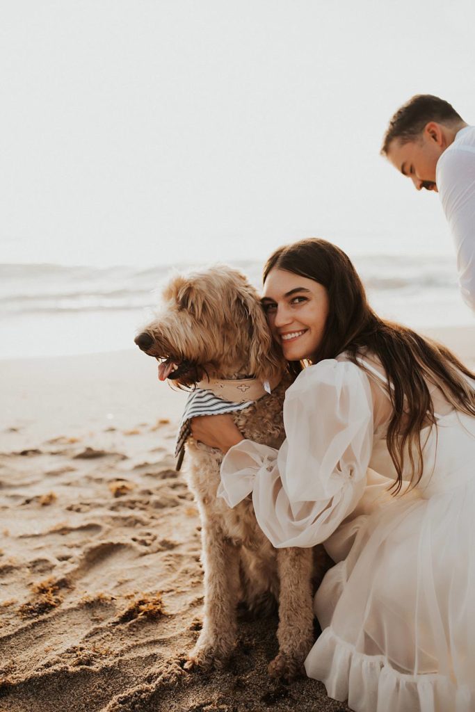Bride and groom with golden doodle dogs on beach