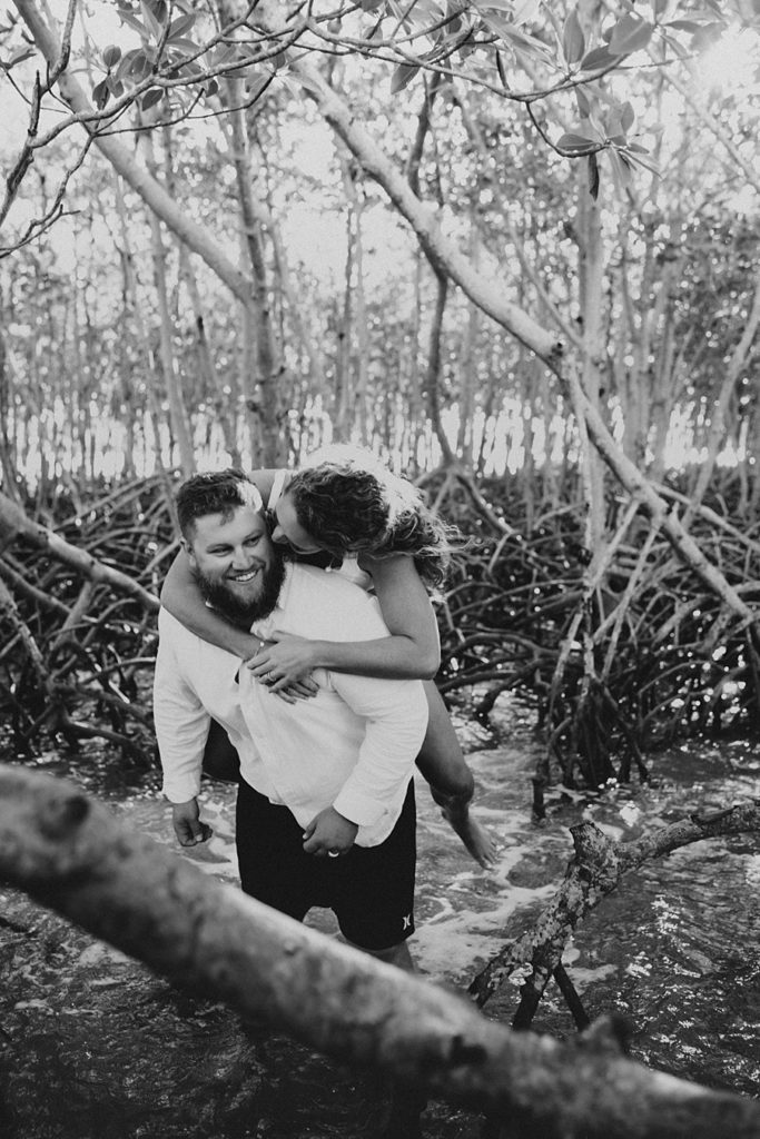 Bride on groom's back in mangrove trees