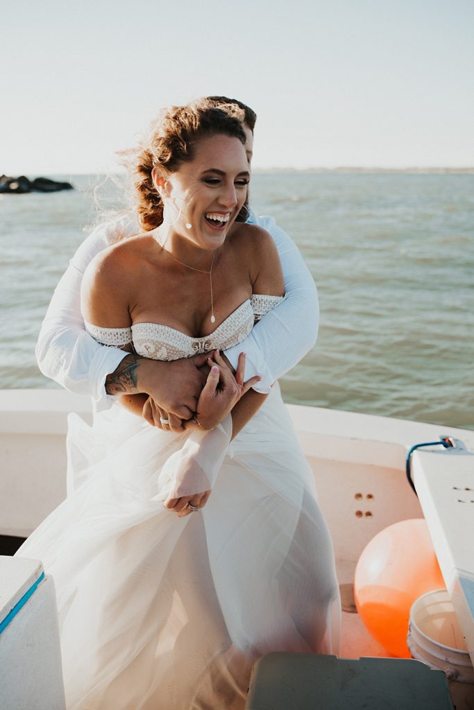Groom hugging bride from behind on boat