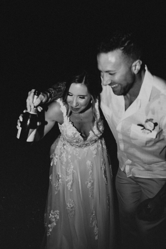 Bride and groom drinking champagne out of the bottle