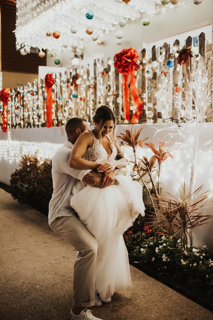 Groom picking up bride during night of lights