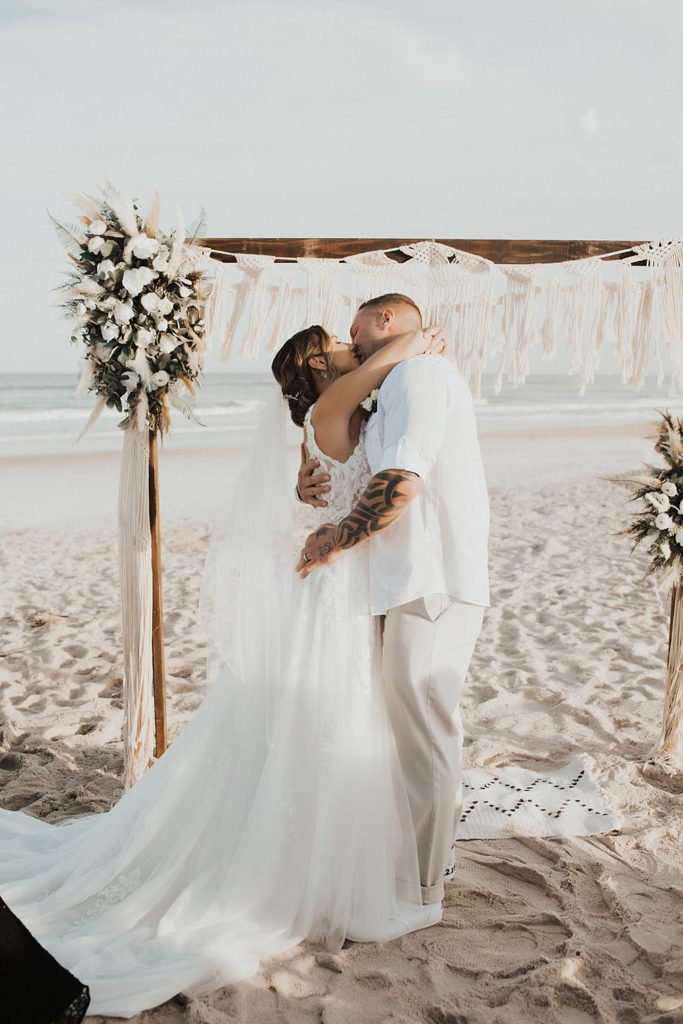 Bride and groom's first kiss at beach wedding