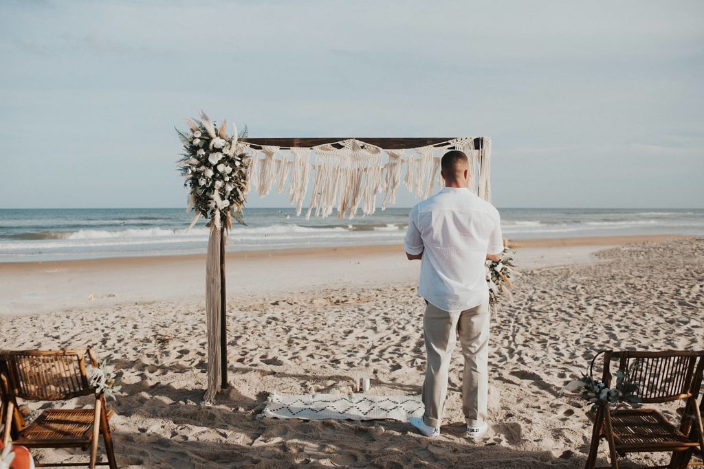 Groom waiting for bride to walk down the aisle at beach ceremony