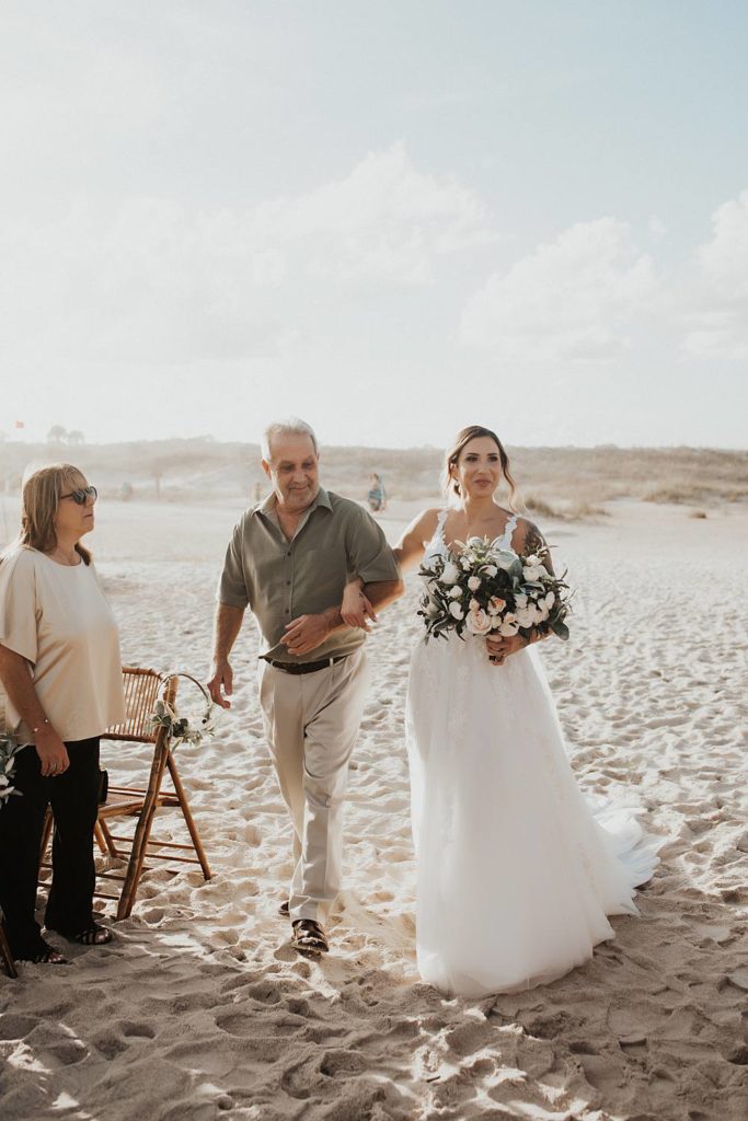 Father walking bride down the aisle at beach wedding