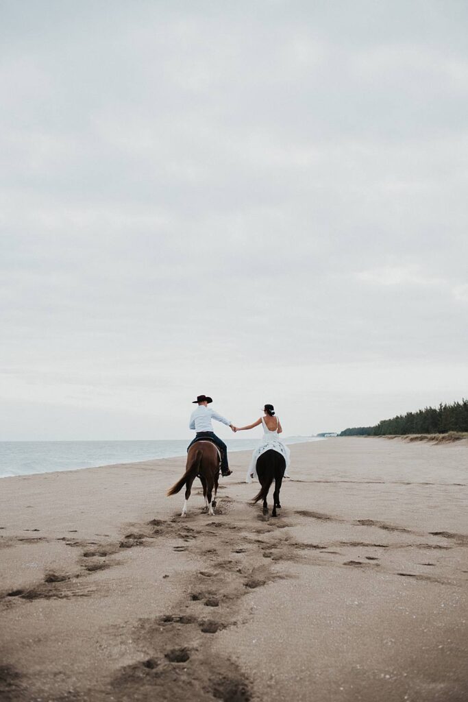Bride and groom riding horses at the beach in Florida for their elopement