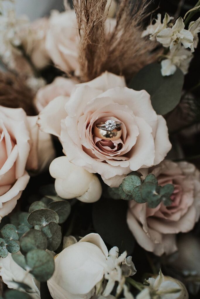 Round cut diamond engagement ring sitting inside a pale pink rose floral bouquet